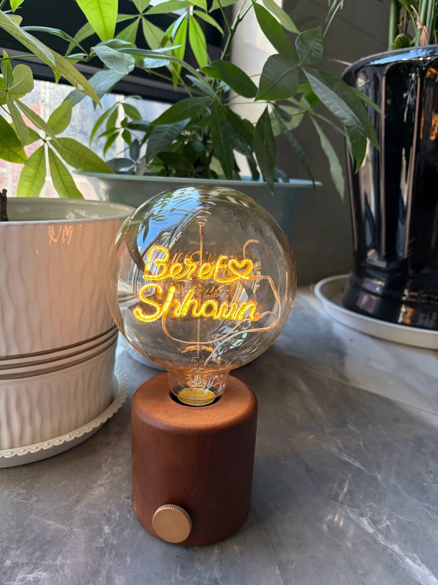 Close-up of custom couple name filament bulb lamp with heart design on walnut wood base