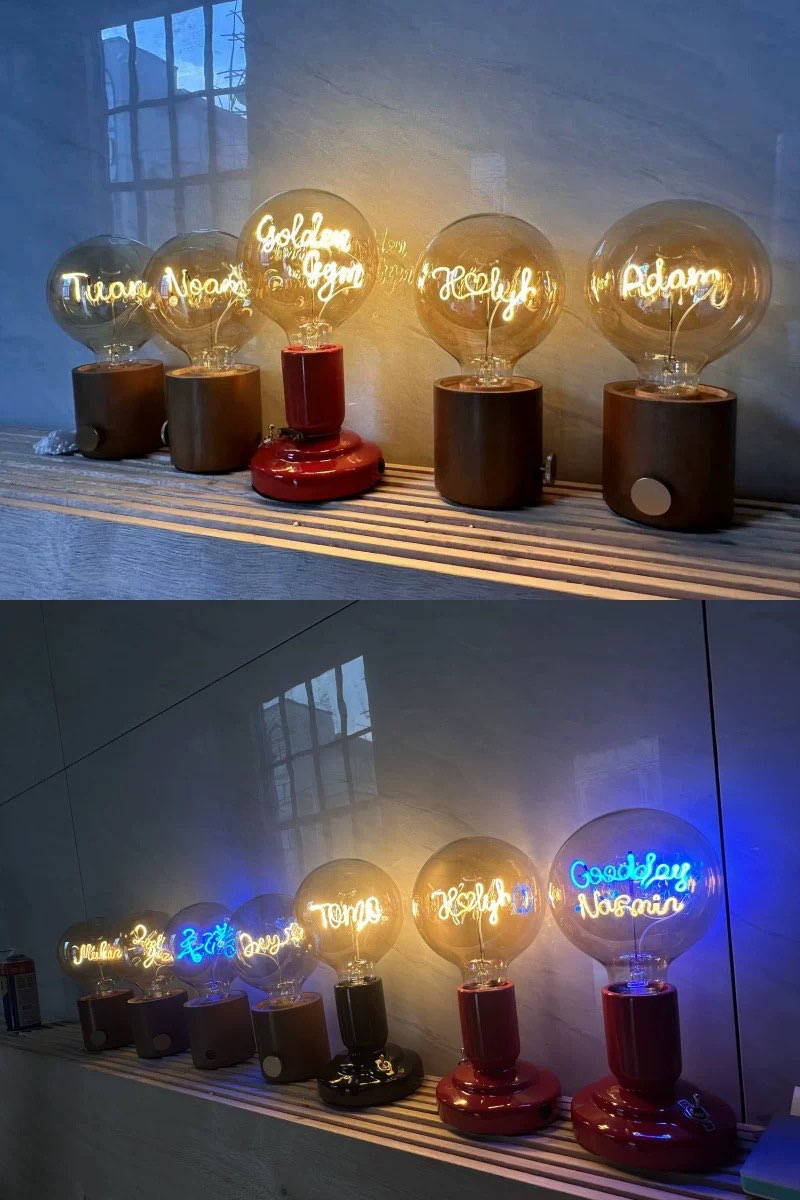 Collection of personalized name light bulb lamps displayed on a shelf, warm ambient glow